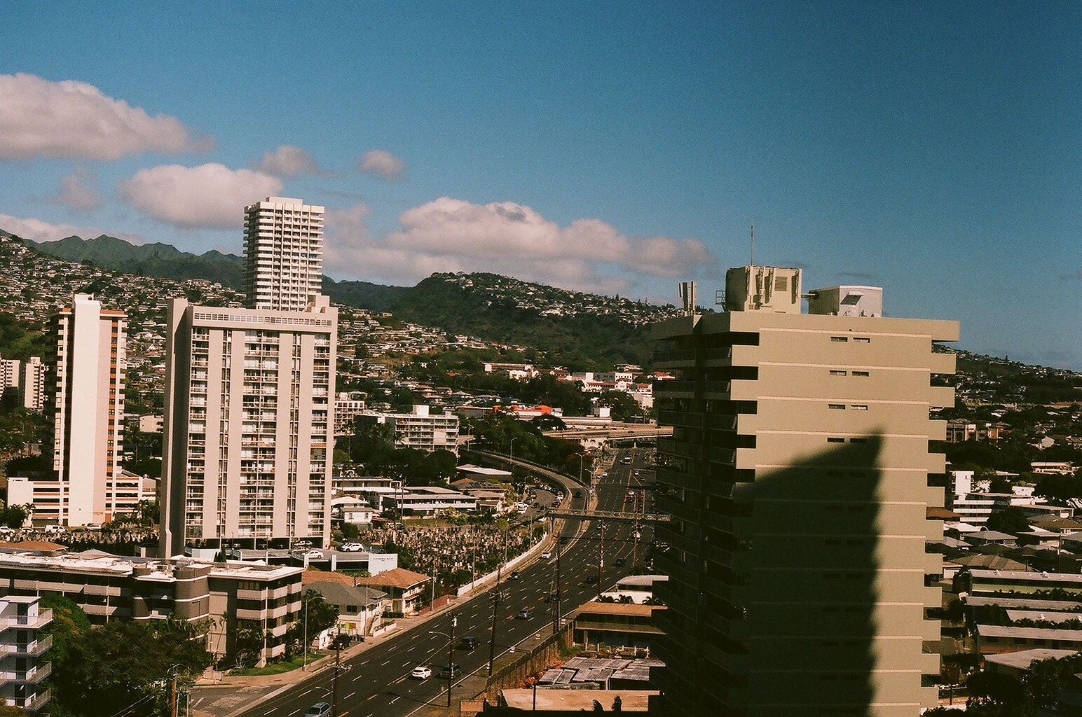 Honolulu high-rises and a curving freeway below green hillside neighborhoods