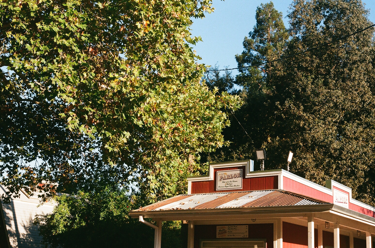 Red roadside ice cream stand called The Parlor tucked under tall trees