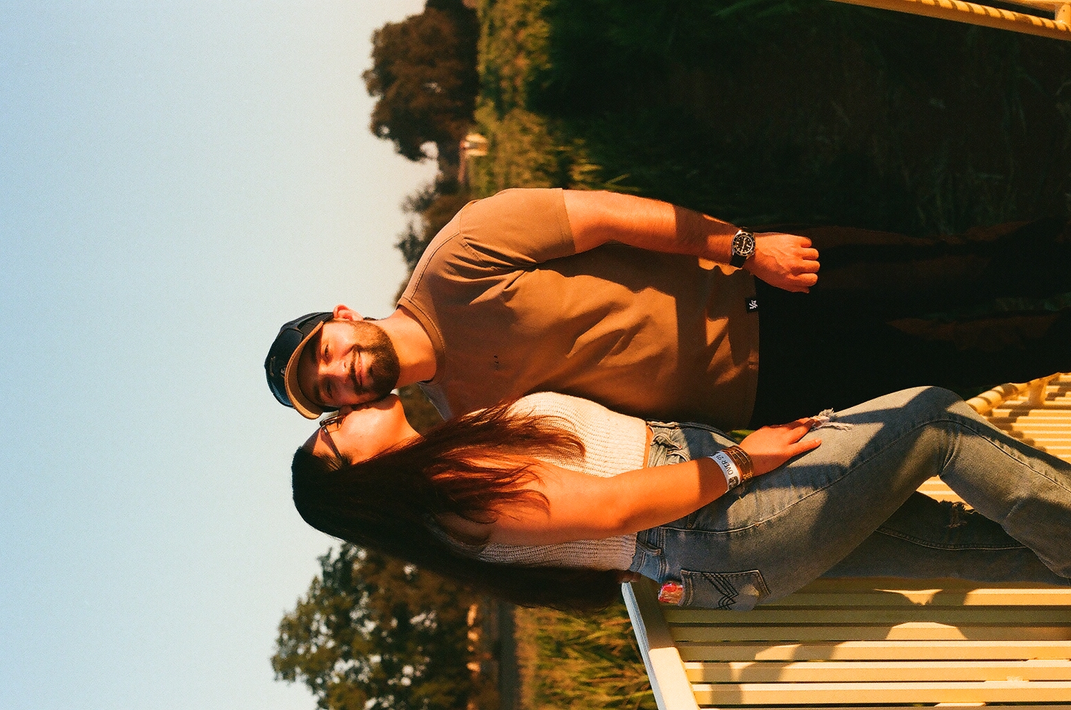 A couple sitting close together on yellow farm equipment in warm evening light